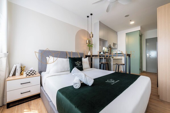 Una habitación de hotel moderna con una cama bien hecha, un escritorio y una kitchenette.