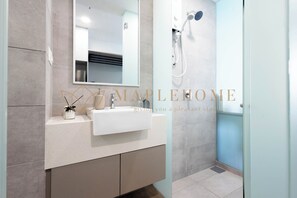 Un baño moderno con un espejo grande, un lavabo y una zona de ducha.