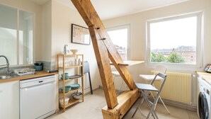 Una cocina compacta con lavavajillas, estantes de madera, un tendedero y una ventana con vistas a edificios.