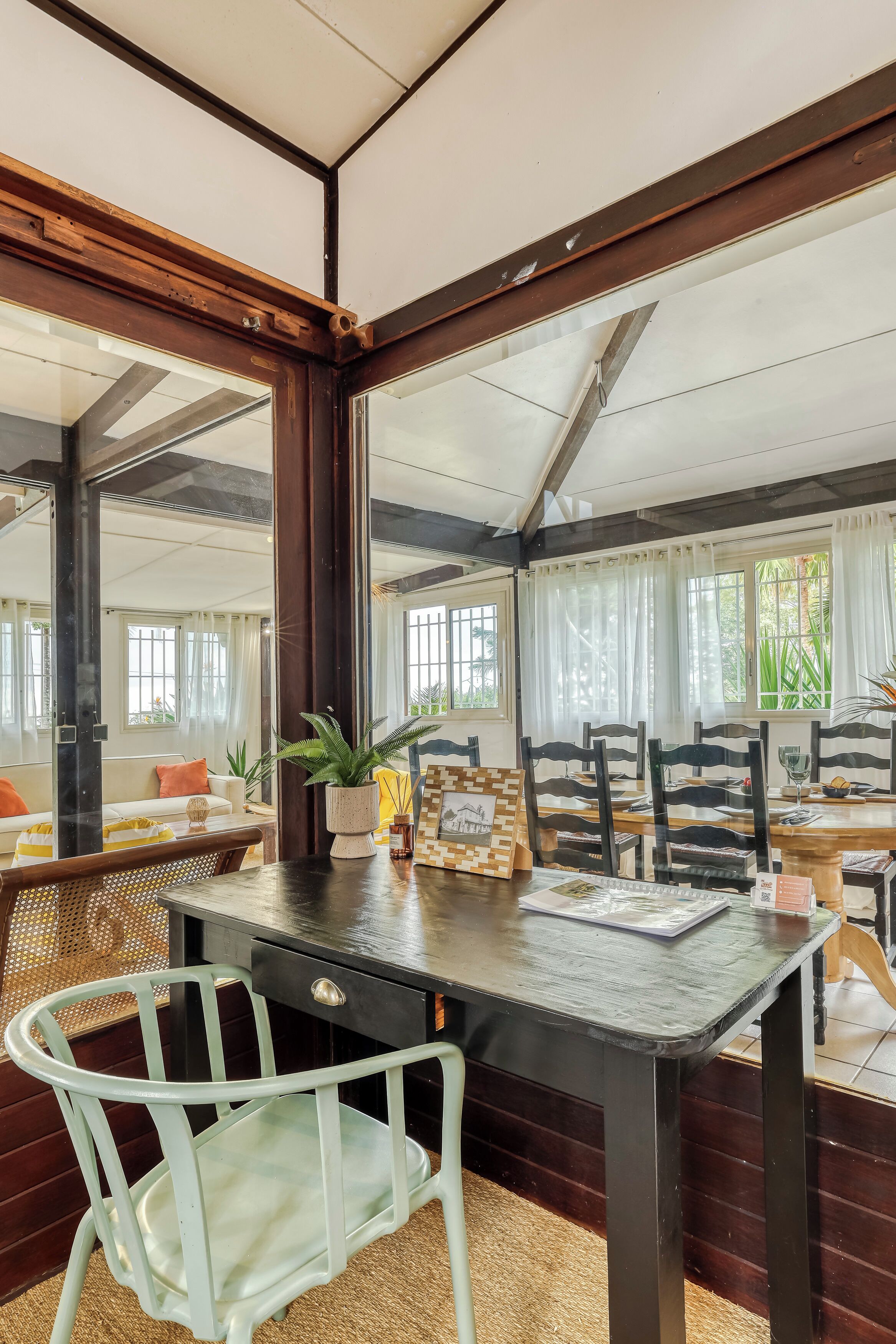 Un comedor con una mesa de madera, sillas y un espejo grande que refleja la habitación.
