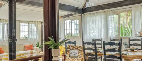 Un comedor con una mesa de madera, sillas y un espejo grande que refleja la habitación.