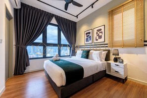Ein modernes Hotelzimmer mit einem großen Bett, einem Nachttisch und Blick auf die Stadt durch große Fenster.