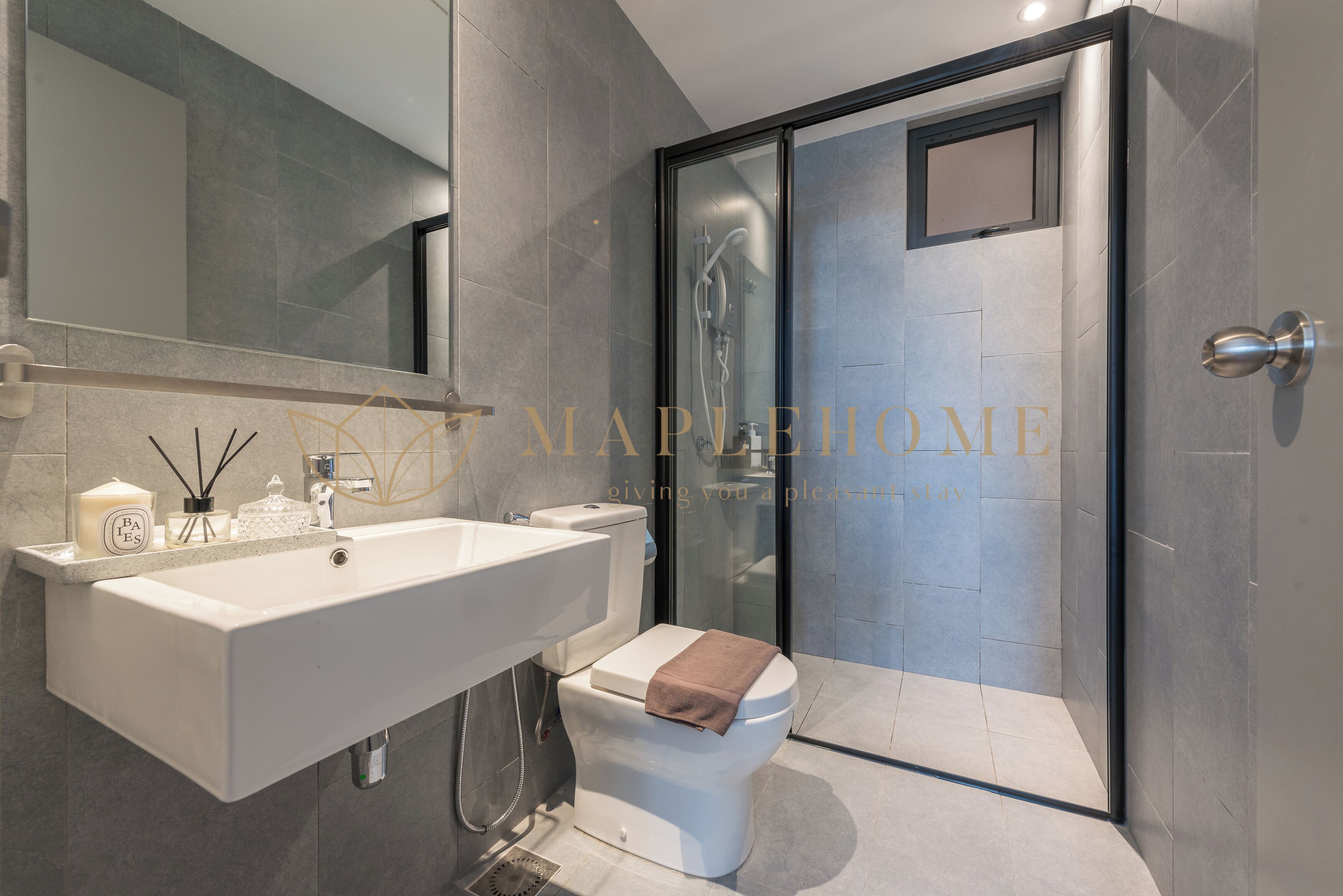 Un baño moderno con un lavamanos grande, inodoro y ducha con mampara de vidrio.