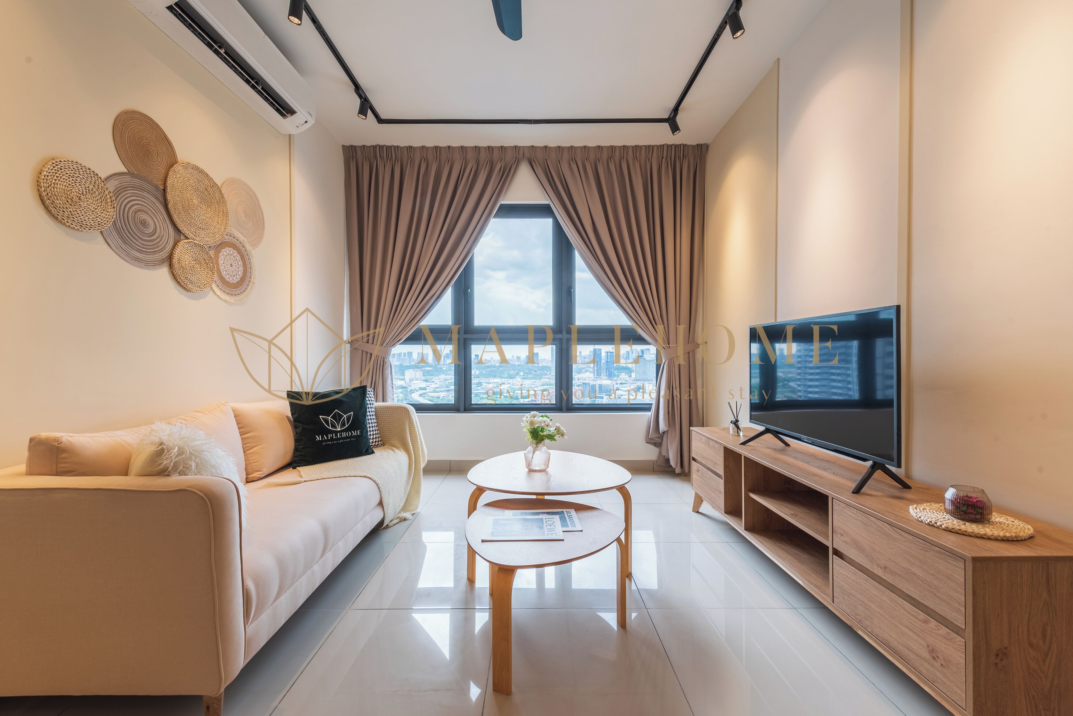 A modern living room with a sofa, a coffee table, a TV, and a view of the cityscape through large windows.