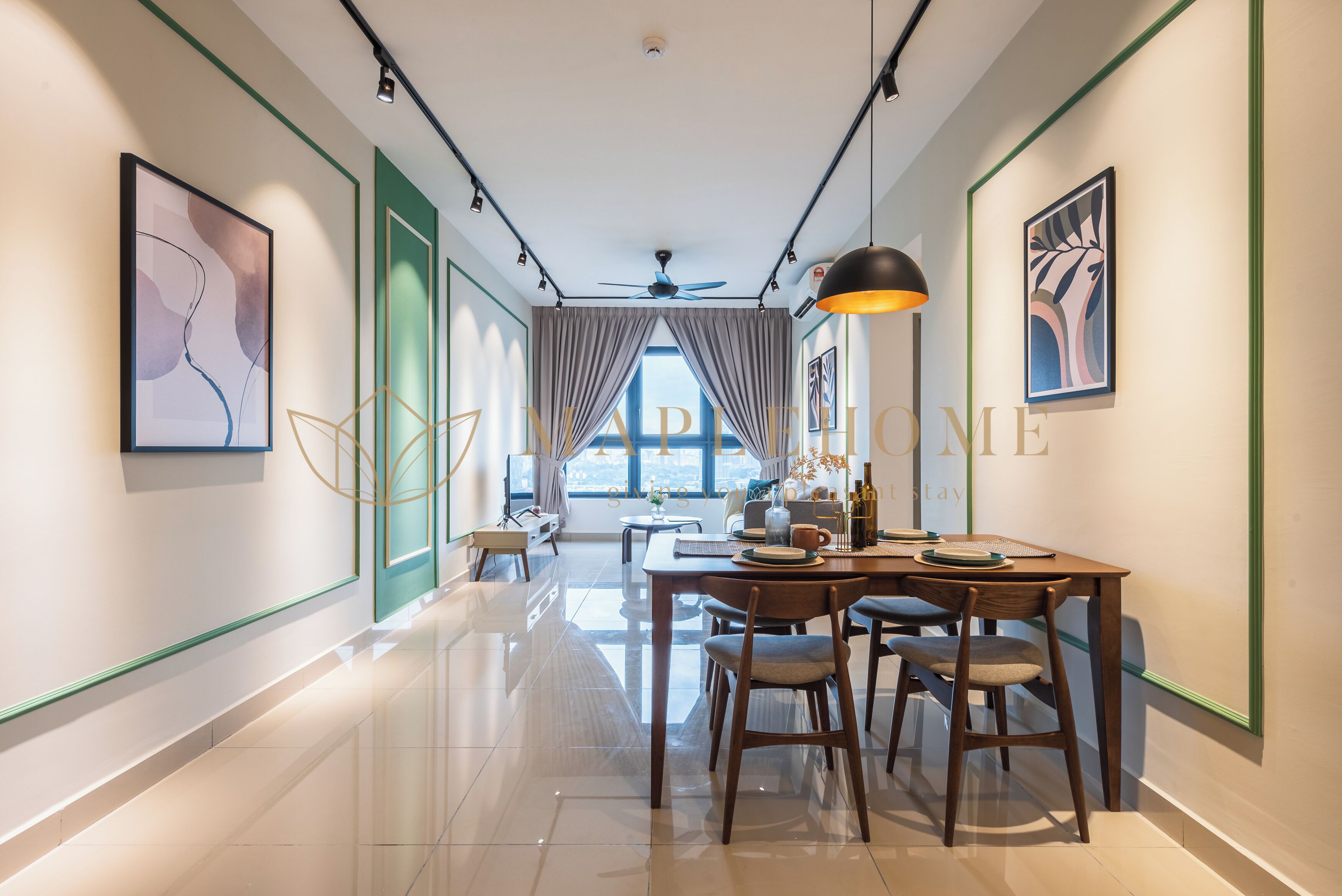 Un couloir d’hôtel moderne avec un espace repas comprenant une table et des chaises en bois, un ventilateur de plafond et des œuvres d’art accrochées aux murs.