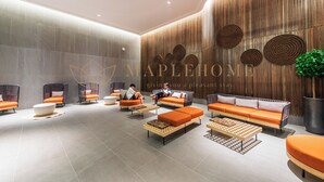 A modern hotel lobby with seating areas, a reception desk, and a large wooden wall with circular patterns.