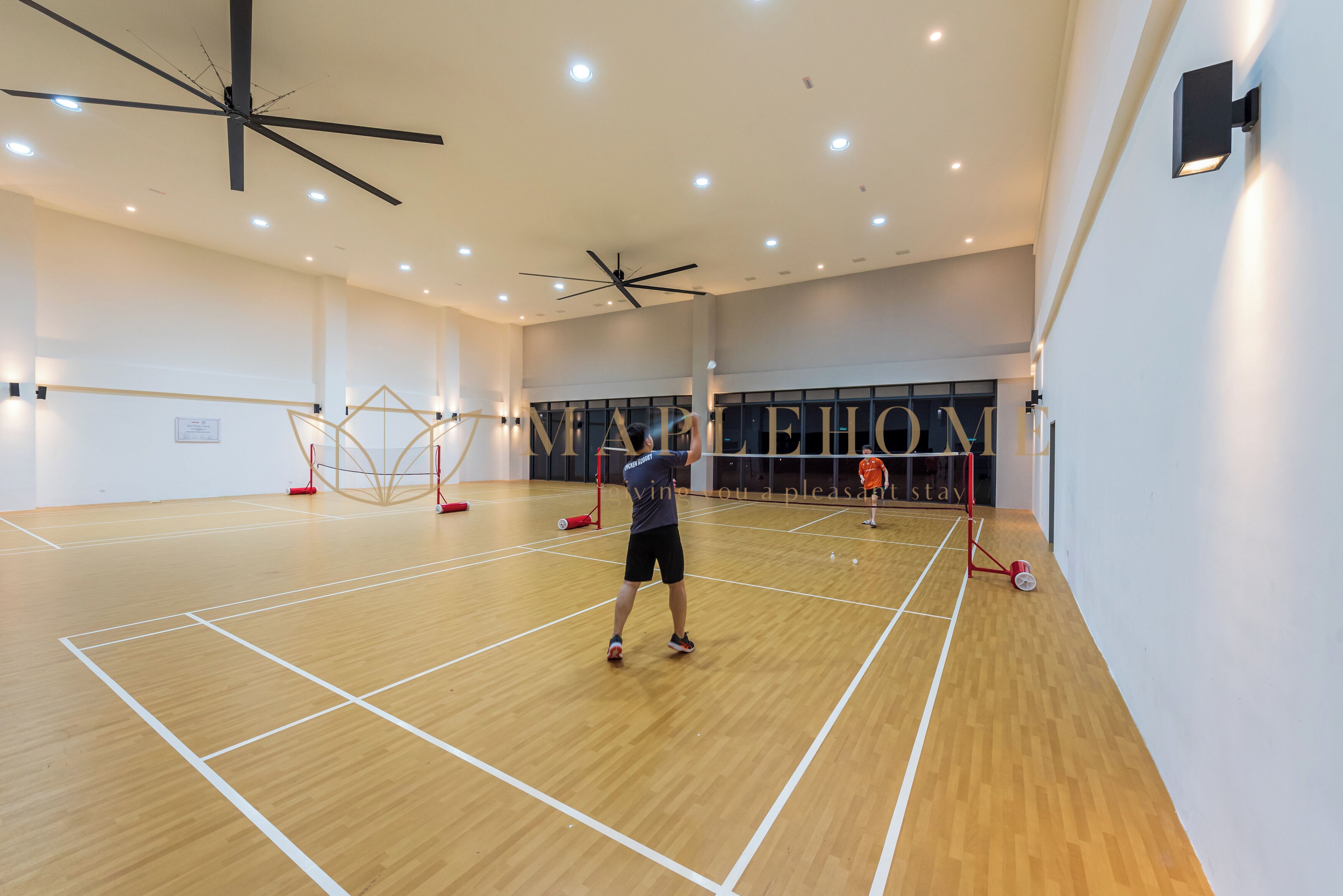 Eine Turnhalle mit Holzboden, Deckenventilatoren und einem Basketballkorb.