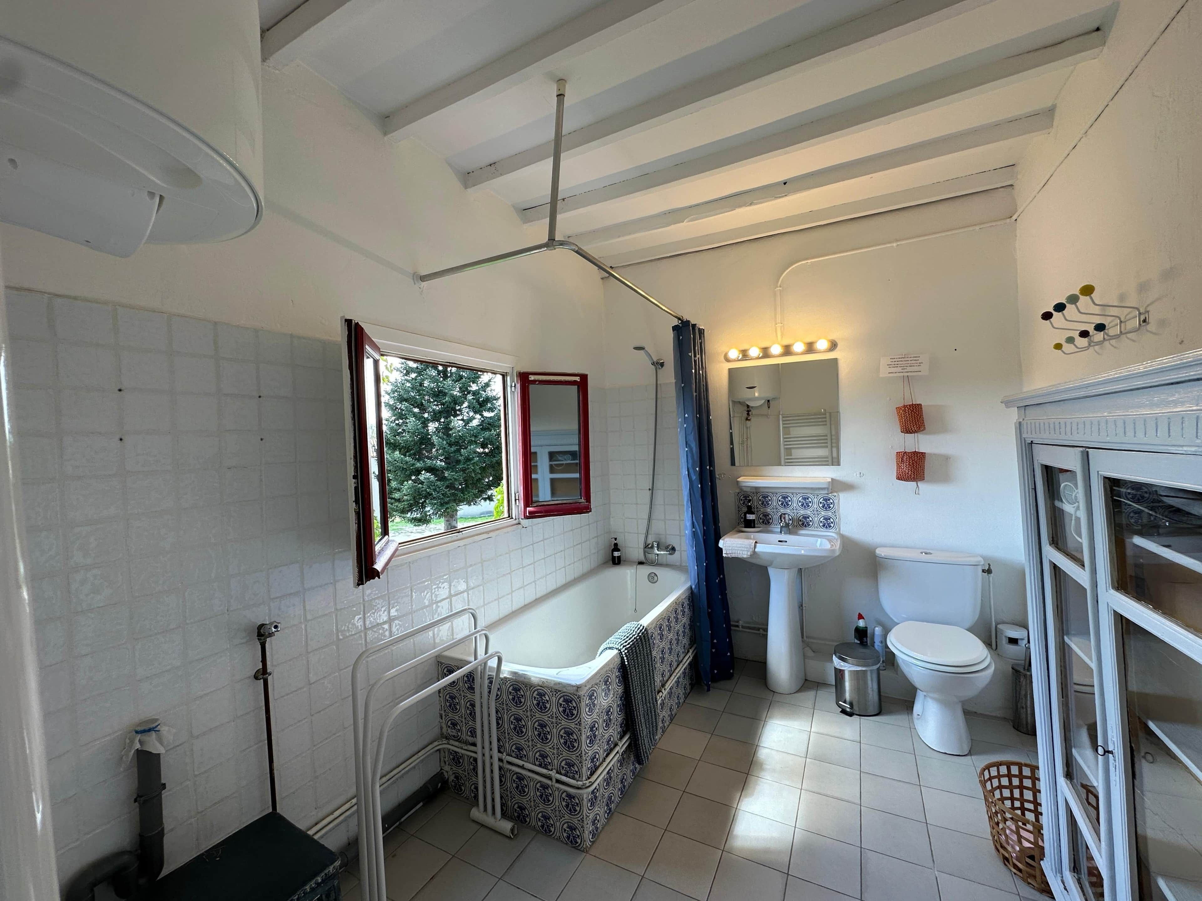 A bathroom with a bathtub, toilet, sink, and a window with a view of trees.