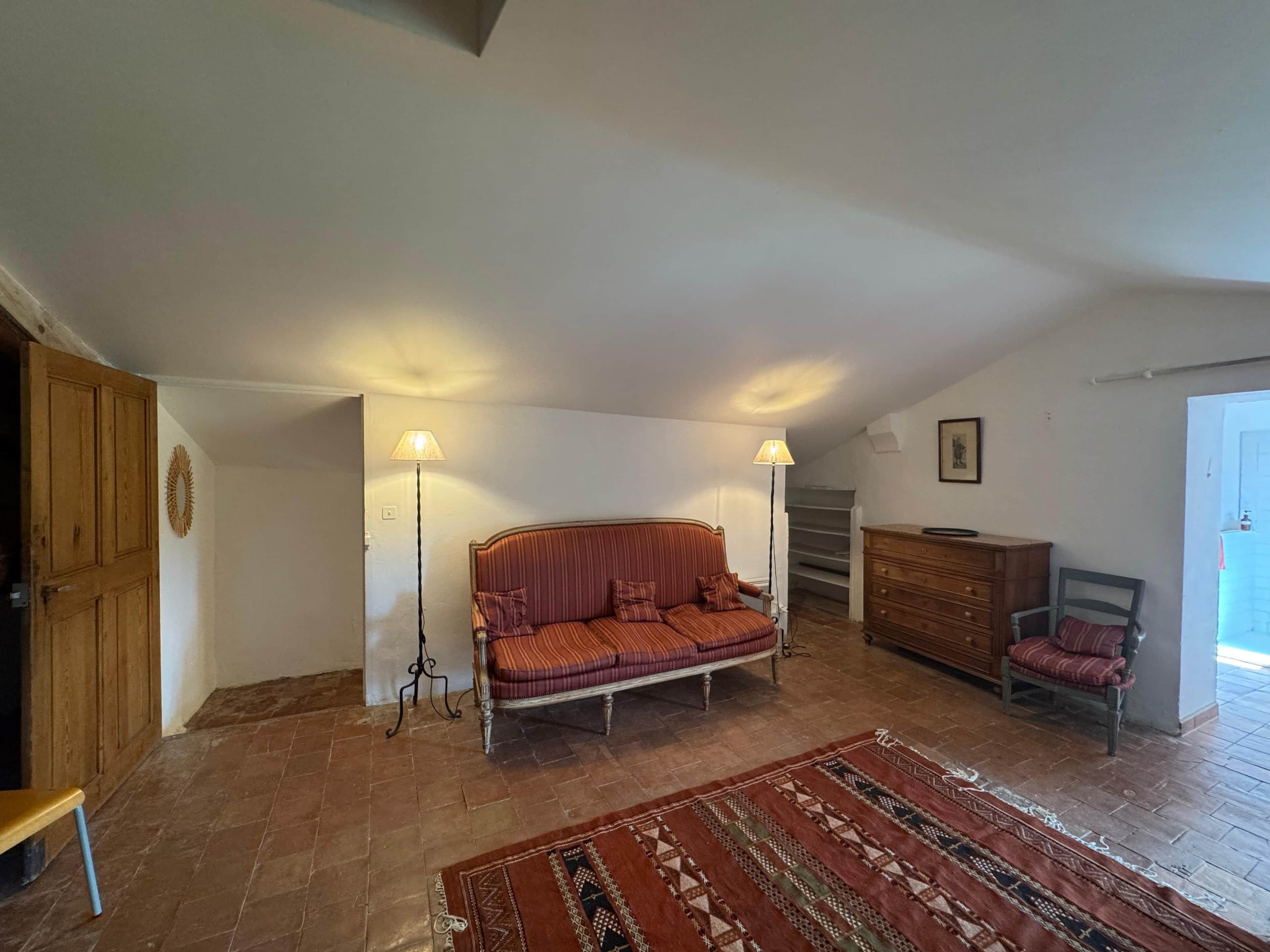 Une pièce chaleureuse avec un canapé à rayures, une commode en bois, une chaise et un tapis à motifs.