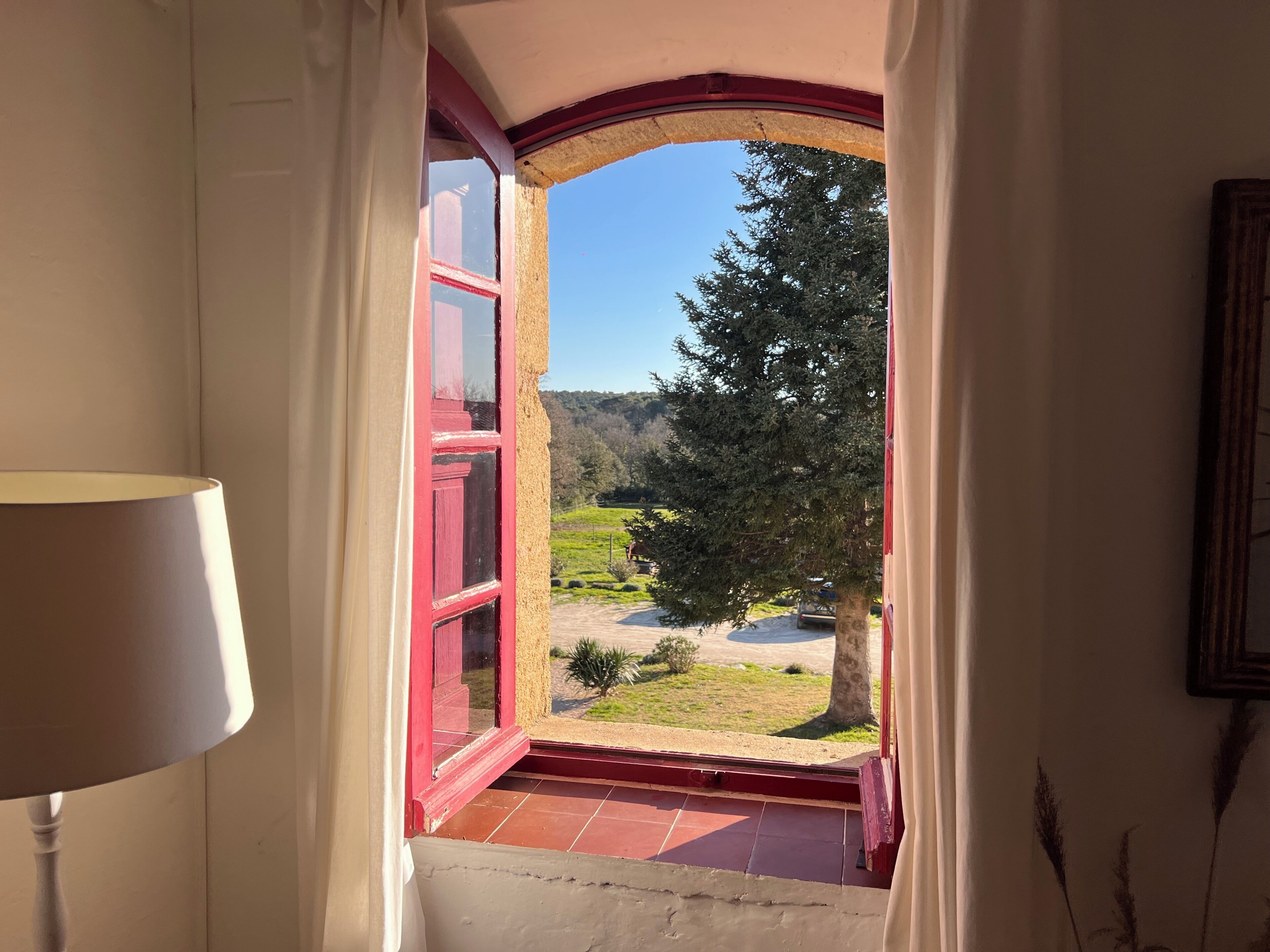 Ein Zimmer mit Blick durch ein Fenster mit roten Rahmen, einer Lampe und einer Tür.