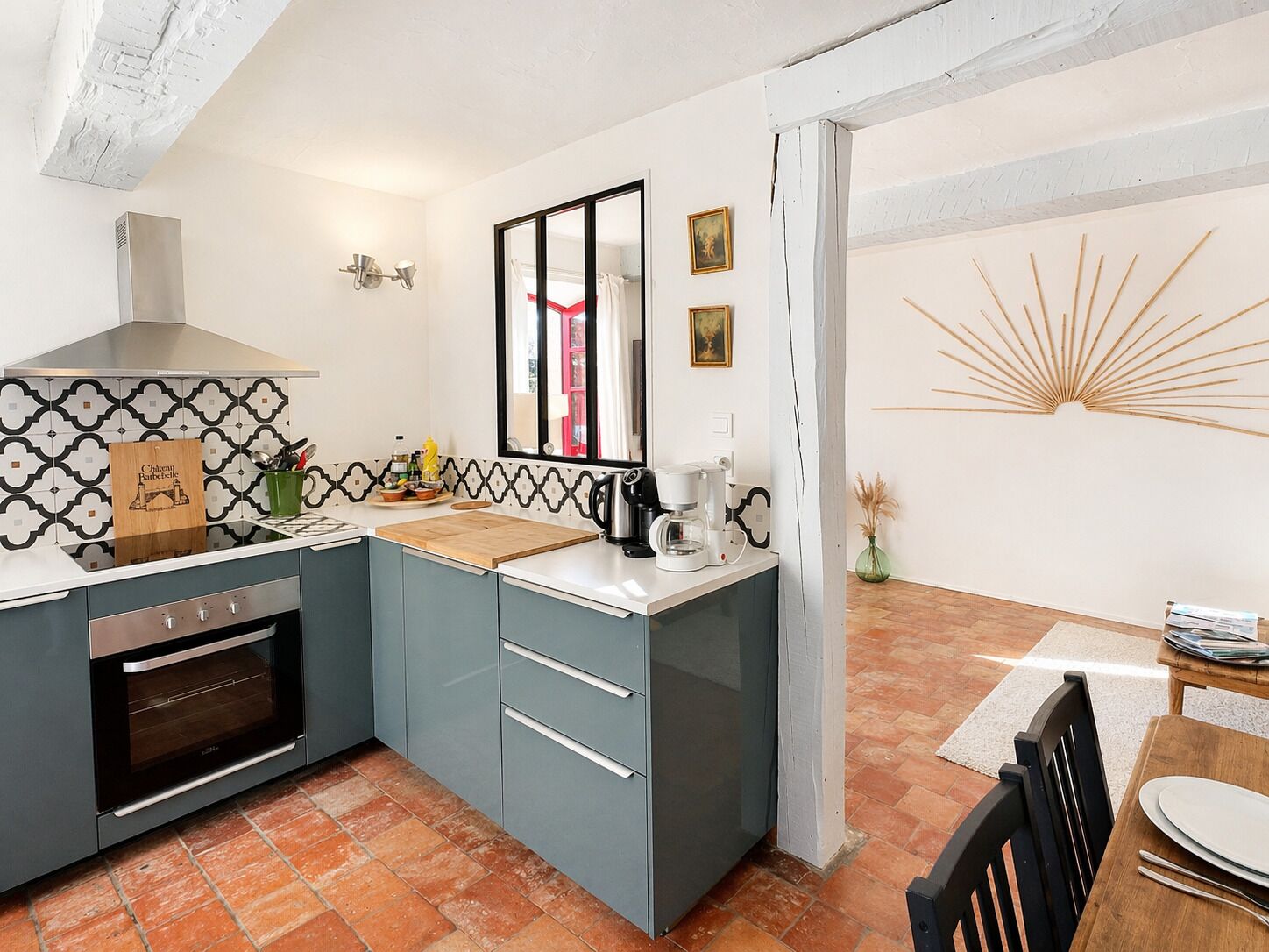 A compact kitchen with a built-in oven, a coffee maker, and a cutting board on the counter.