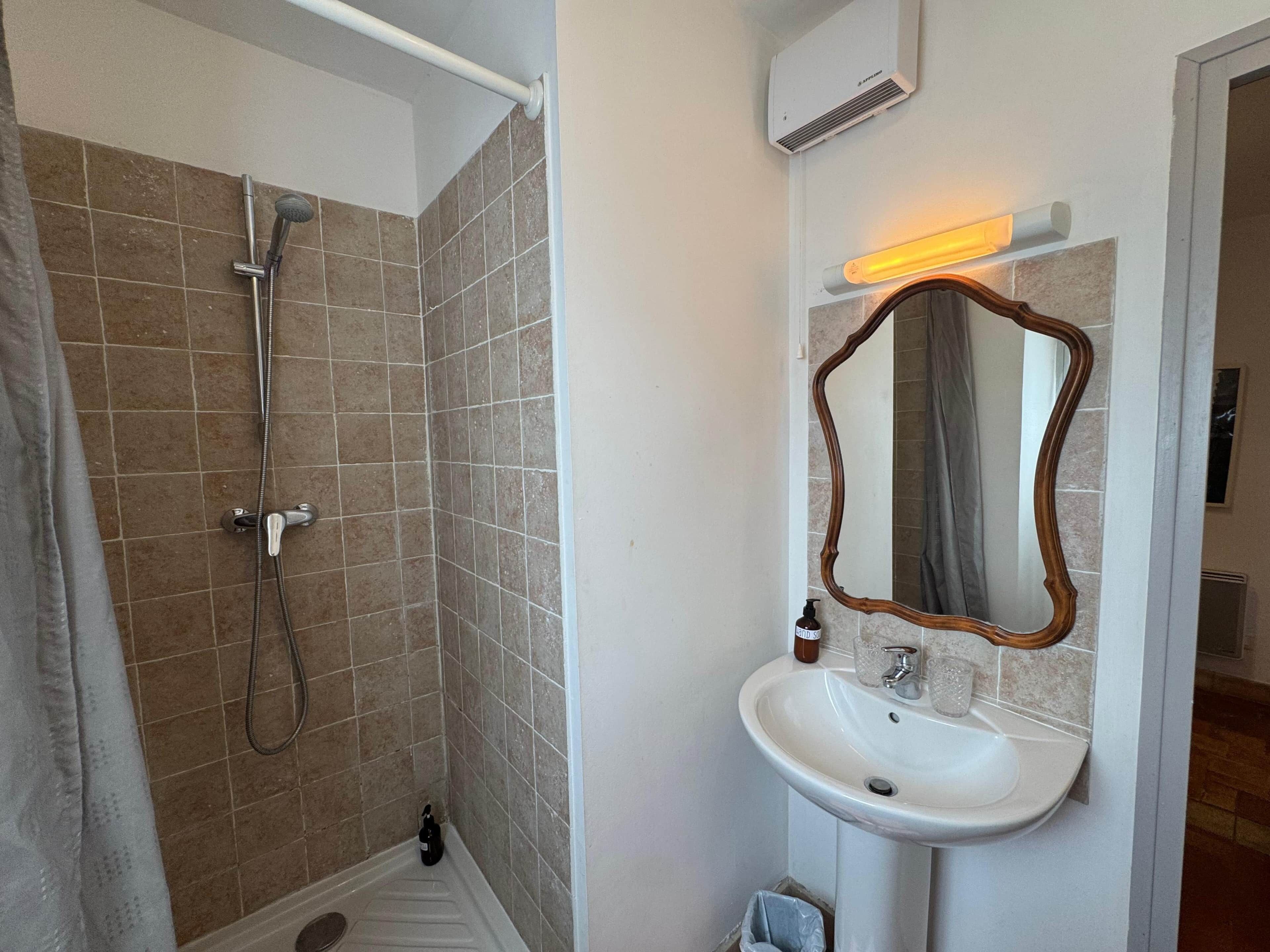 Ein Badezimmer mit Dusche, Waschbecken und Spiegel.