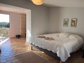 Ein Schlafzimmer mit Bett, Blick ins Freie und einer Tür zum Balkon.