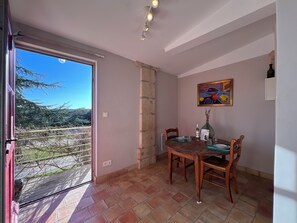 Ein Essbereich mit Tisch für zwei Personen, einem Bild an der Wand und Blick durch eine Glastür.