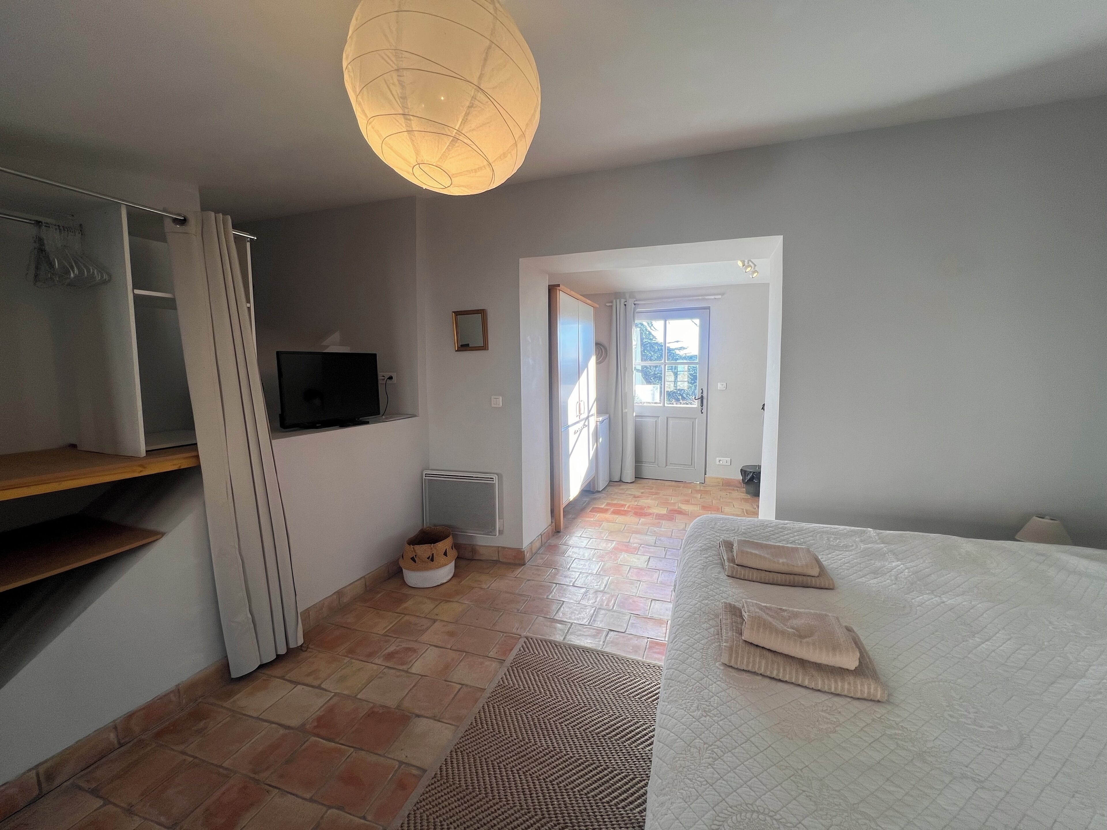 Une chambre à coucher comprenant un lit, un téléviseur, un radiateur et une porte donnant sur une autre pièce.