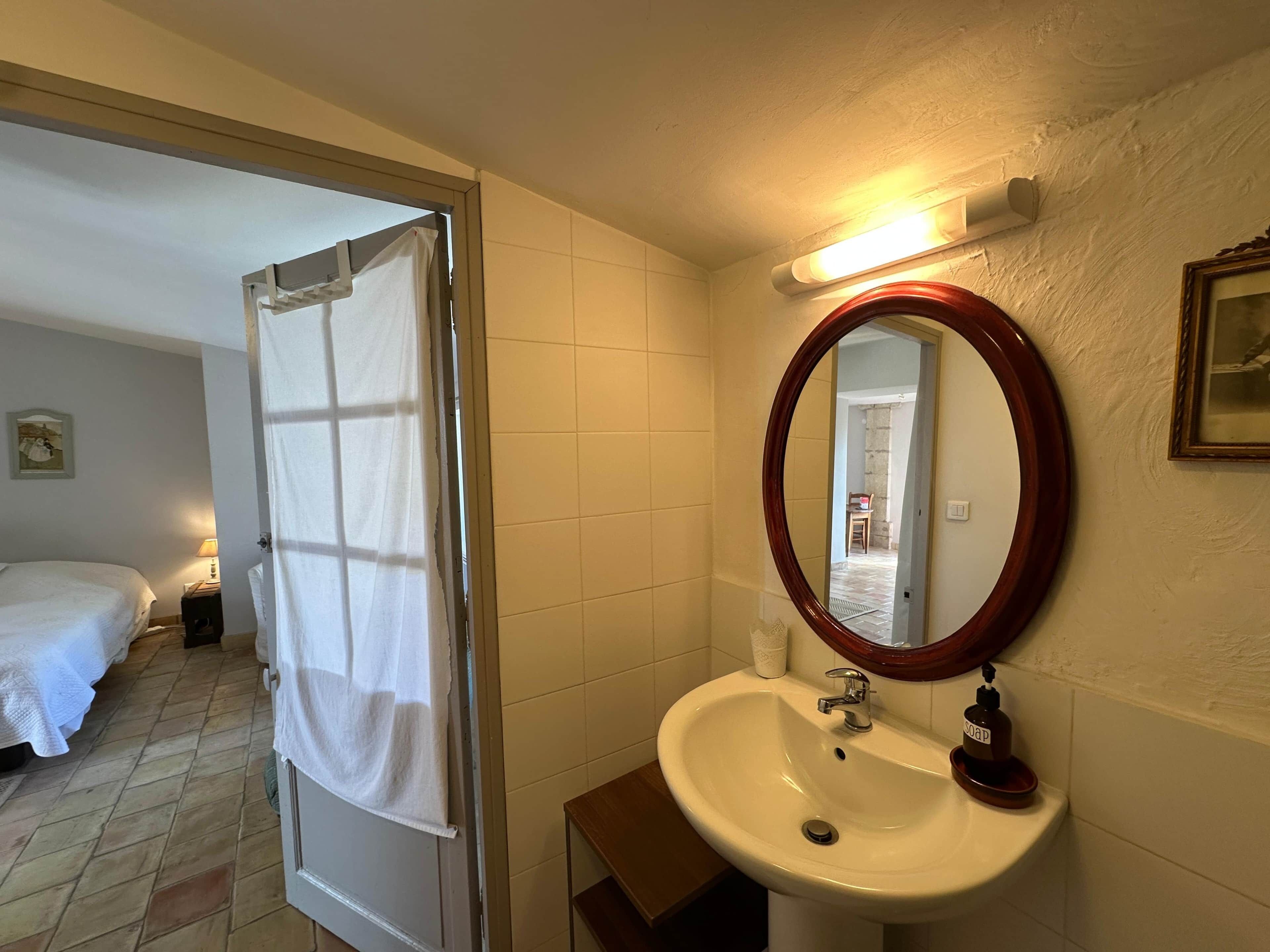 Een hotelbadkamer met een witte wastafel, een spiegel en een handdoek aan een deur.