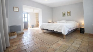 Een slaapkamer met een bed, een radiator, een deur naar een andere kamer en een lamp.