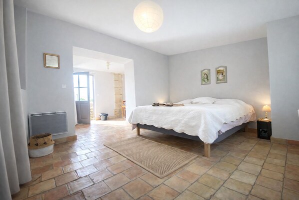Ein Schlafzimmer mit Bett, Heizkörper, einer Tür zu einem anderen Raum und einer Lampe.