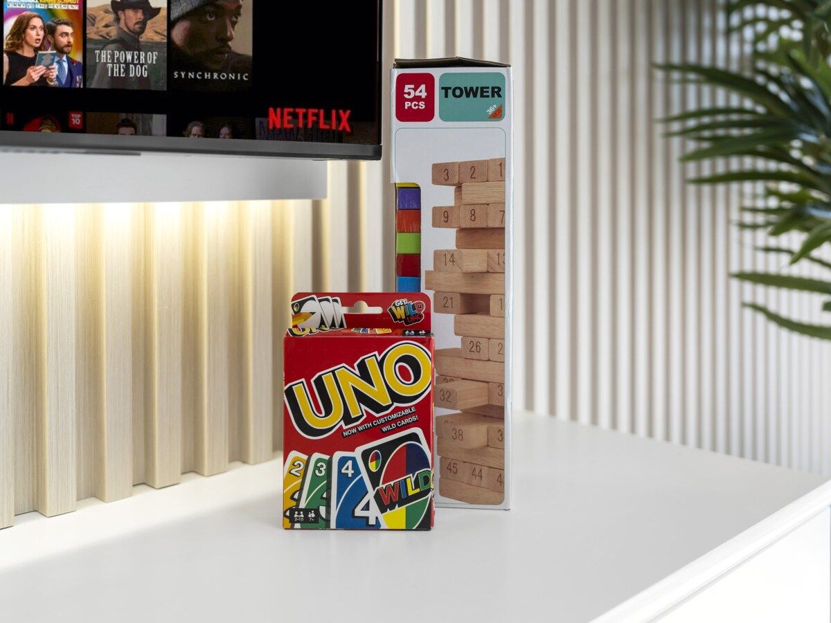 Une partie d’UNO se déroule sur une surface blanche, et un téléviseur diffuse en arrière-plan du contenu de Netflix.