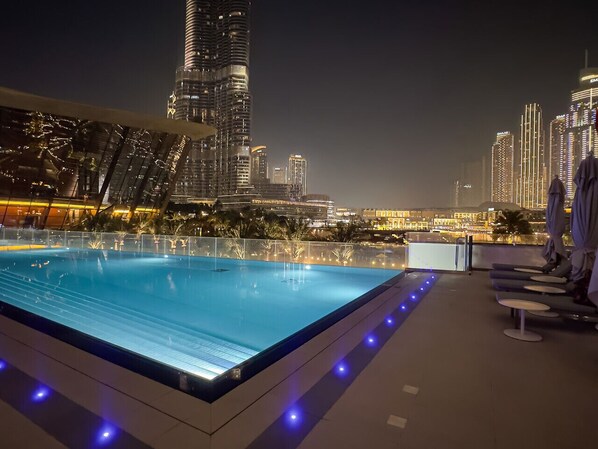 A rooftop pool with a view of a city skyline at night.