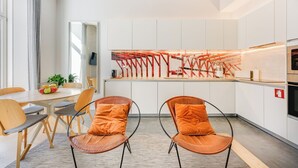 A modern kitchen with white cabinets, a central island, and orange chairs.