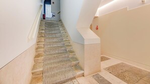 A staircase with a patterned carpet, a fire extinguisher, and a wall-mounted light fixture.