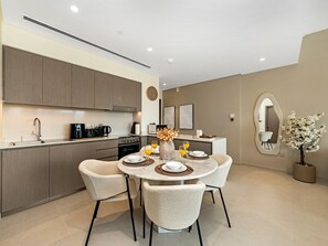 A modern kitchen with built-in appliances, a dining area with a round table and chairs, and a large mirror on the wall. - New 1BR | Burj Khalifa Infinity Pool | Dubai Mall (Dubai)