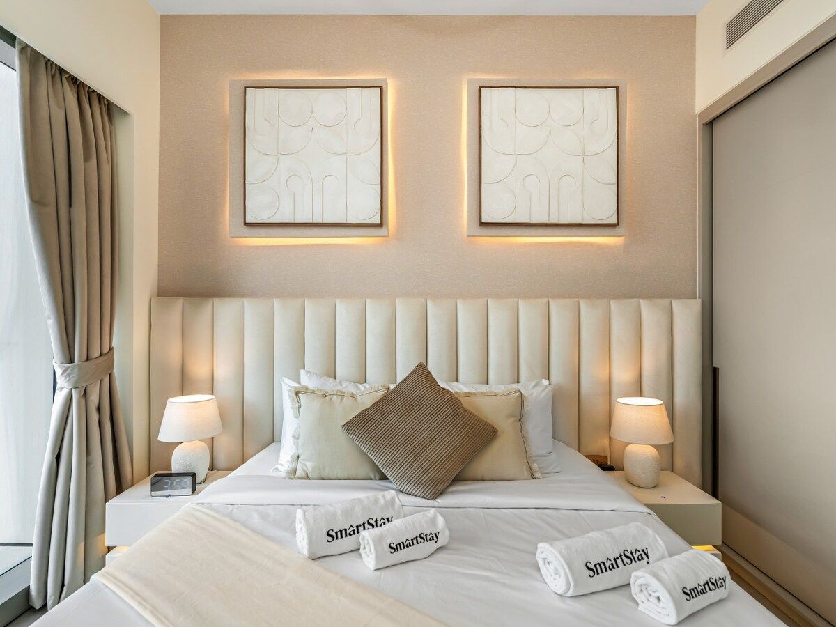 Een hotelkamer met een groot bed, twee bedlampen, een hoofdeinde en twee wandlampen.