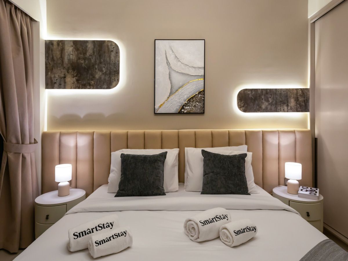 A hotel room with a bed, two bedside tables, a headboard, and a wall-mounted artwork.