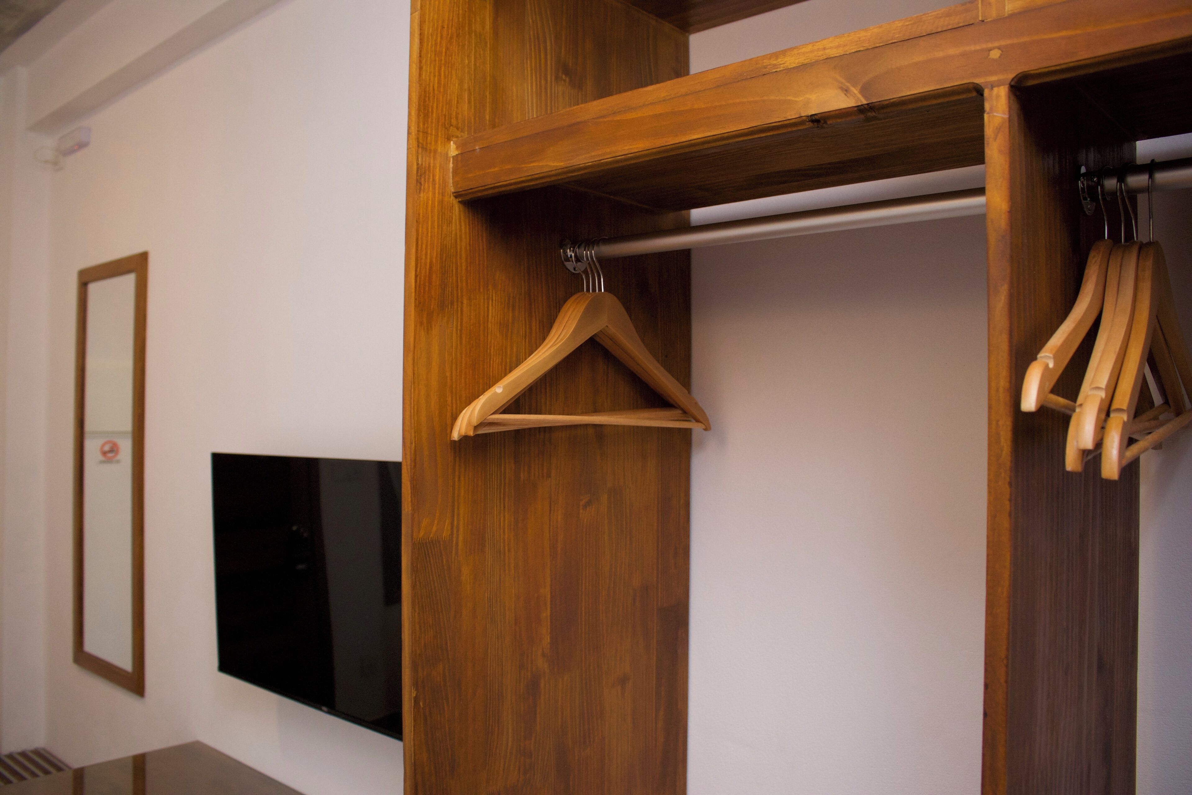 Un armario de madera con espejo y televisor montado en la pared.