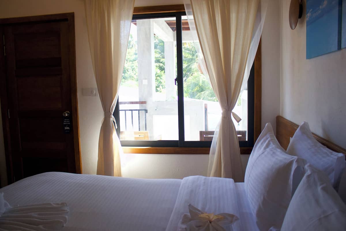 A hotel room with a bed, curtains, a window, and a view of the outside.