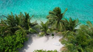 Ranta lähistöllä, valkoista hiekkaa, aurinkotuoleja, aurinkovarjoja