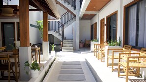 A spacious indoor area with a central staircase, wooden benches, and potted plants. - Oshi Boutique  (Felidhoo)