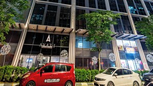 A high-rise building with a prominent 'AYAT' sign at the entrance, surrounded by other tall buildings.