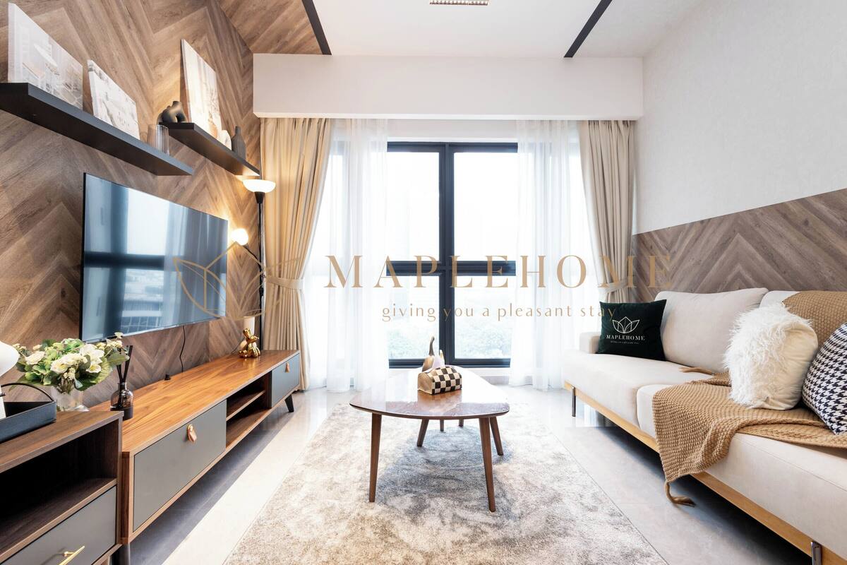Een moderne woonkamer met een grote flatscreen-televisie, houten planken, een salontafel en een bank met decoratieve kussens.