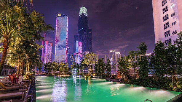 A nighttime view of a hotel pool area with a city skyline in the background.
