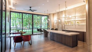 A modern kitchen with a central island, large windows, and a dining area with red chairs.