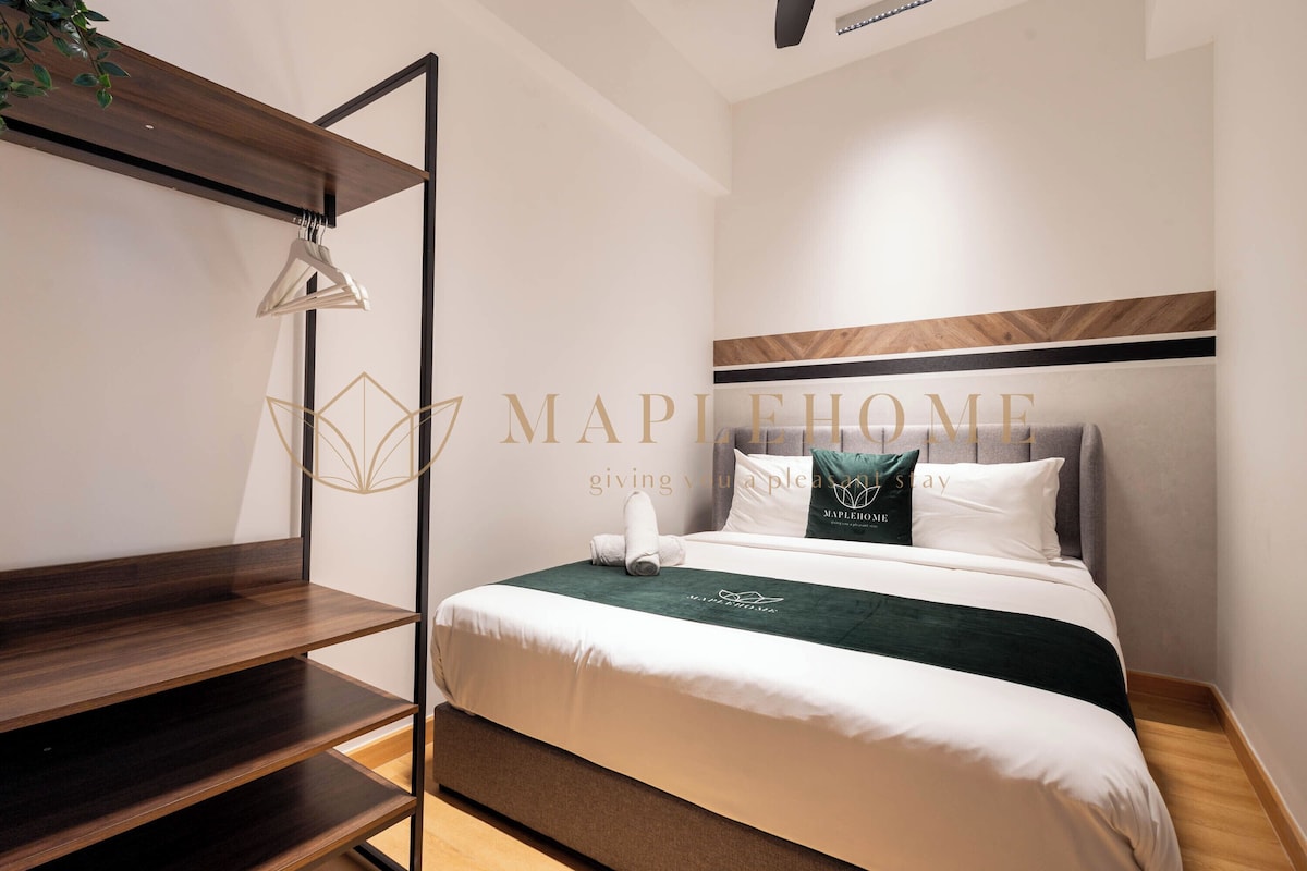 A neatly arranged hotel room with a bed, a wooden shelf, and a hanging garment rack.
