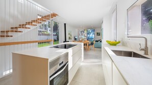 Une cuisine moderne dotée d’un îlot central, d’un coin repas avec une table et des chaises, et d’un escalier avec des marches en bois.