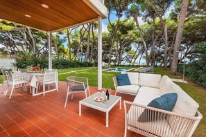 Une terrasse extérieure avec une table blanche, des chaises et un canapé.