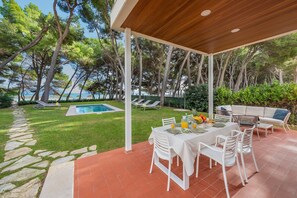 Un espace extérieur abrité, aménagé pour les repas, avec une piscine et des chaises longues.
