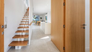 Un intérieur moderne avec un escalier en bois, un coin cuisine et une grande porte en bois.