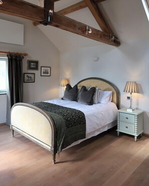 A bedroom with a large bed, two bedside tables, a wooden ceiling, and framed pictures on the wall. - Relaxing Retreat in Shropshire (Eaton Constantine)