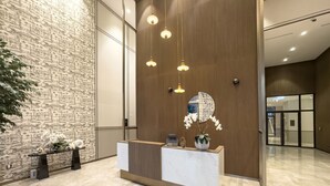 A reception desk with a marble top, a wooden panel wall, and hanging pendant lights.