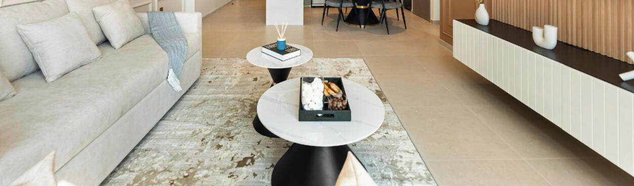 A modern living room with a sofa, a coffee table, and a dining area with a table and chairs.