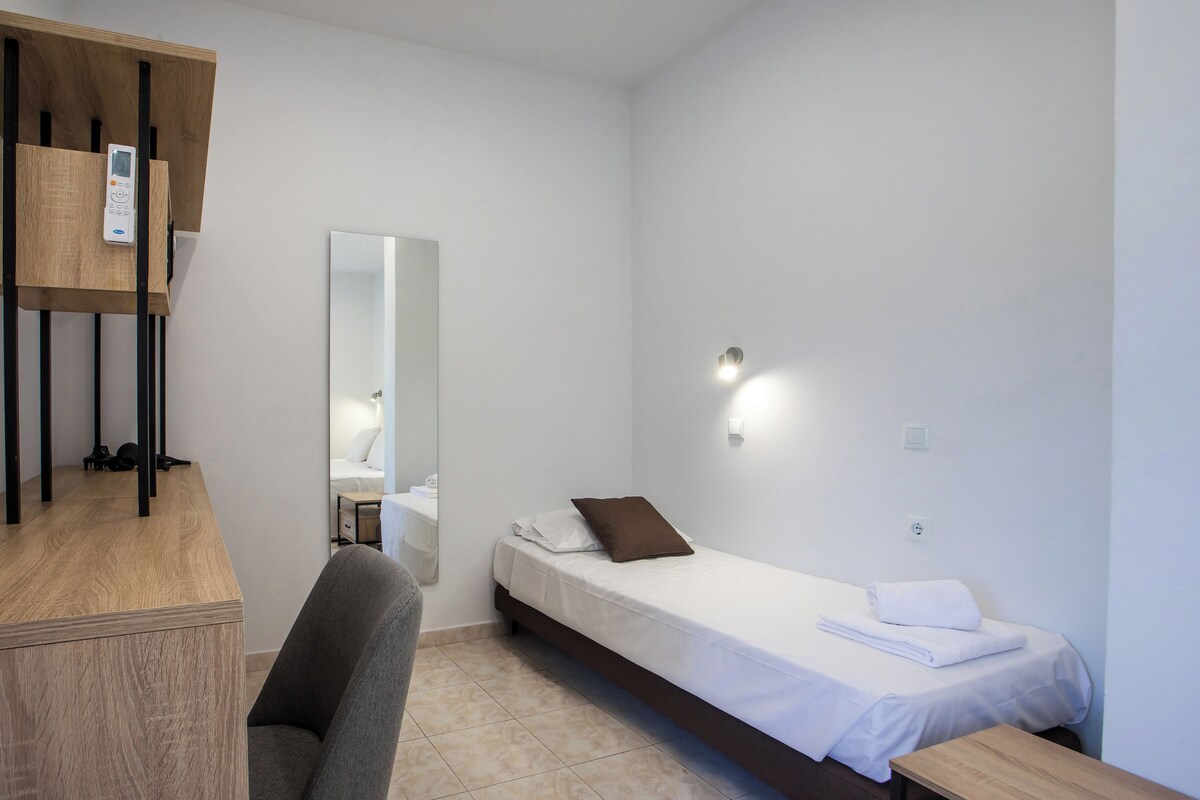 A small, clean room with a bed, a desk, and a chair.
