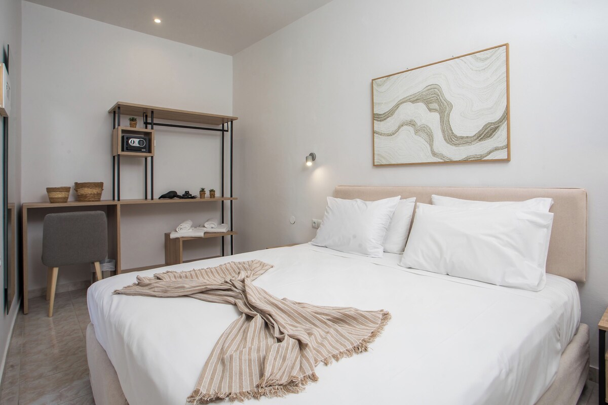 A neatly arranged bedroom with a bed, a desk, and a shelf with a radio.