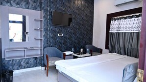 A hotel room with a bed, a desk with a chair, a TV, and a wardrobe. - Hotel Ramarsh Palace (Ayodhya)
