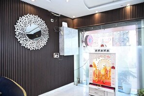 A modern interior with a decorative wall, a reception desk, and a glass partition with a decorative display. - Hotel Ramarsh Palace (Ayodhya)