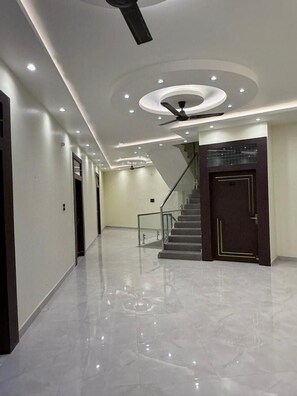 A modern hallway with a polished marble floor, a staircase, and recessed ceiling lighting. - Hotel Ramarsh Palace (Ayodhya)